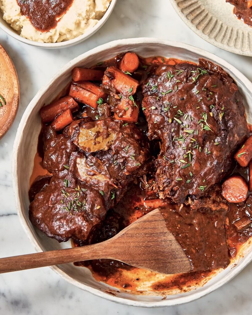 Pot Roast in bowl with carrots, with a serving spoon resting in bowl.