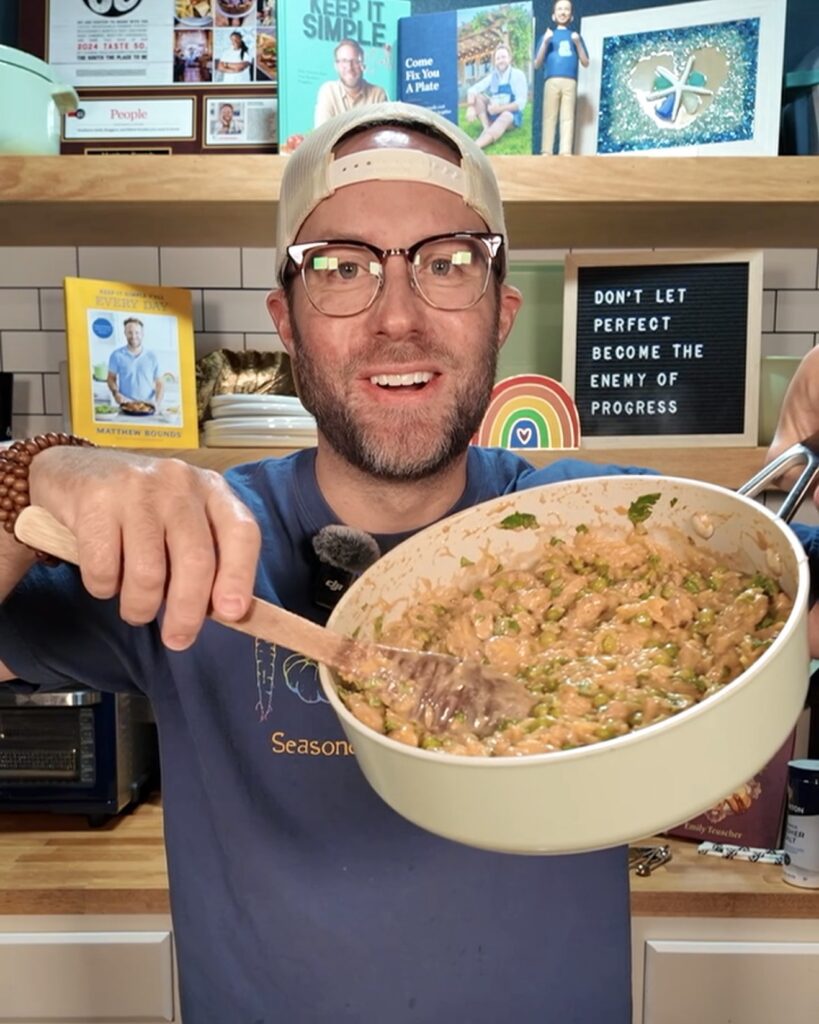Matthew Bounds holding pan of Lemony Parmesan Chicken Orzo in kitchen