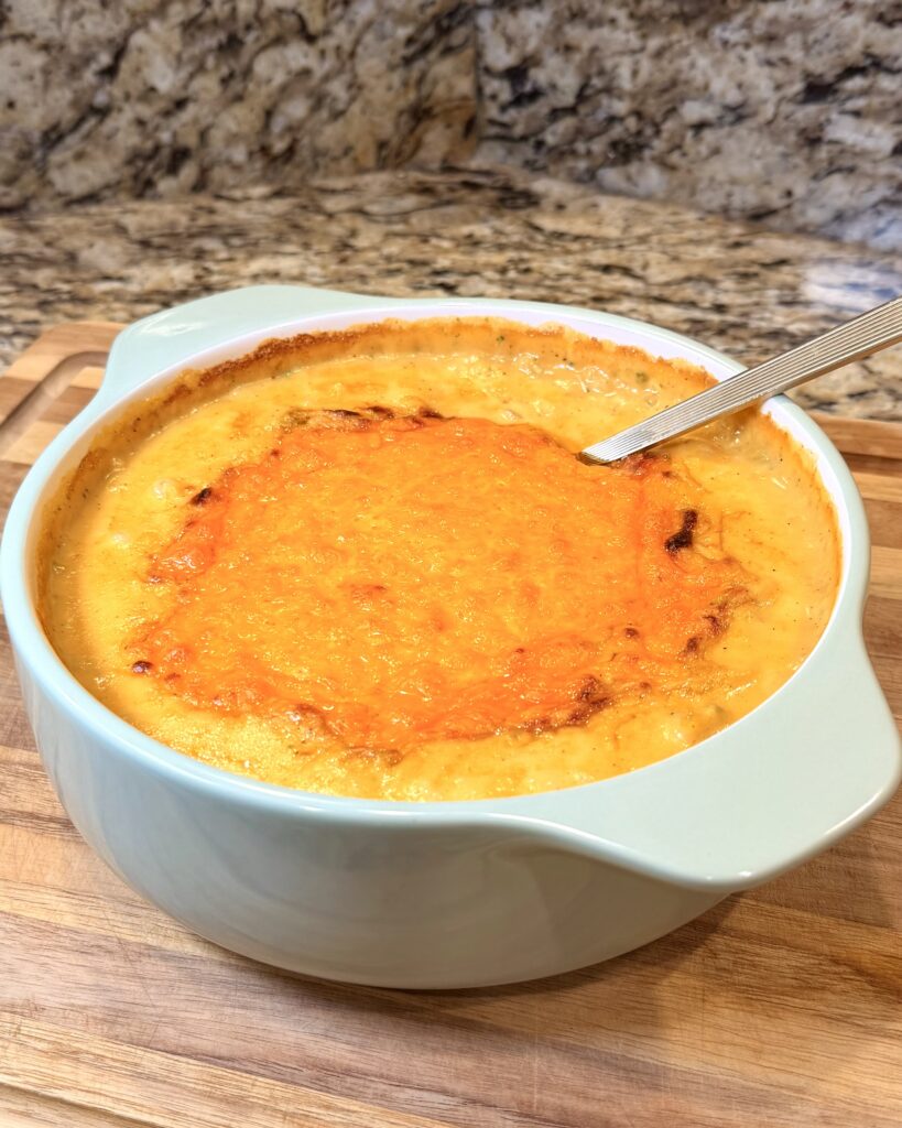 Broccoli and Cheese Casserole made by Your Barefoot Neighbor Matthew Bounds sits in a baking dish on a counter. The casserole is cheesy and rich. 