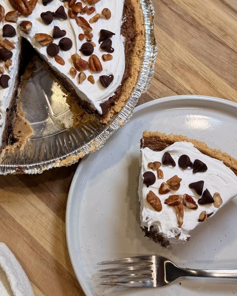 A generous slice of Mississippi Mud Pie from Matthew Bounds's Keep it Simple Y'all Every Day sits on a plate next to the rest of the pie. 
