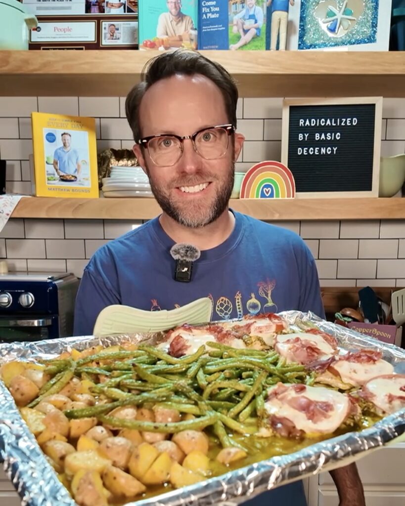 Your Barefoot Neighbor Matthew holding ingredients for Sheet Pan Caprese Chicken in his kitchen.