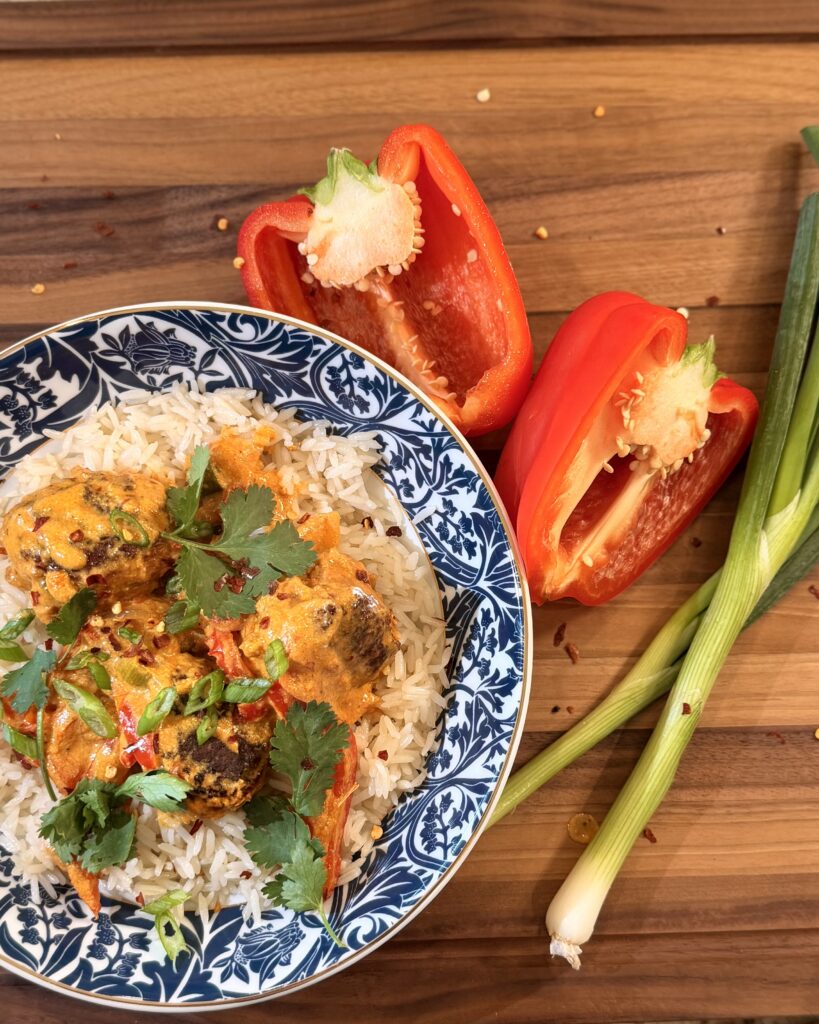 Coconut Curry Chicken Meatballs from Keep It Simple Y'all Every Day in a bowl garnished with cilantro next to a sliced red pepper and green onion