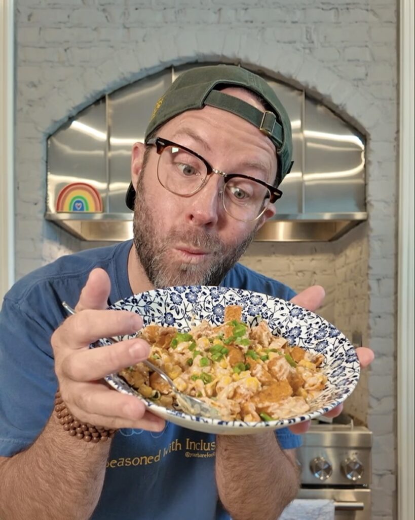 Matthew Bounds, creator of Your Barefoot Neighbor, holds a bowl of hearty Mexican Corn Dip in his kitchen.
