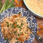 Your Barefoot Neighbor's hearty Mexican Corn Dip topped with green onions sits in a bowl on a table.