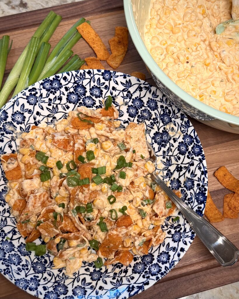 Your Barefoot Neighbor's hearty Mexican Corn Dip topped with green onions sits in a bowl on a table.