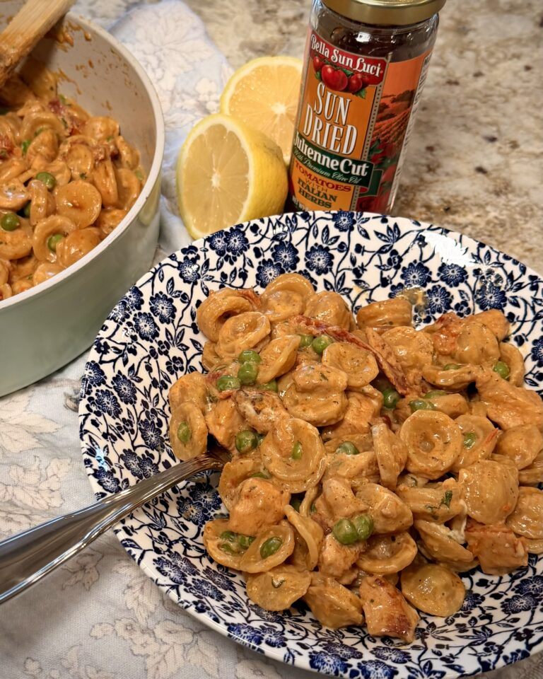 A hearty helping of one pan chickpea pasta, prepared by Your Barefoot Neighbor Matthew Bounds, is on a plate next to sliced lemons and a jar of sun dried tomatoes