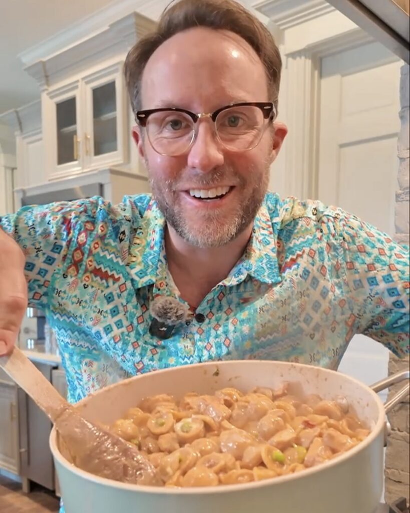 Matthew Bounds, Your Barefoot Neighbor, holds a skillet of chicken pea pasta in his kitchen