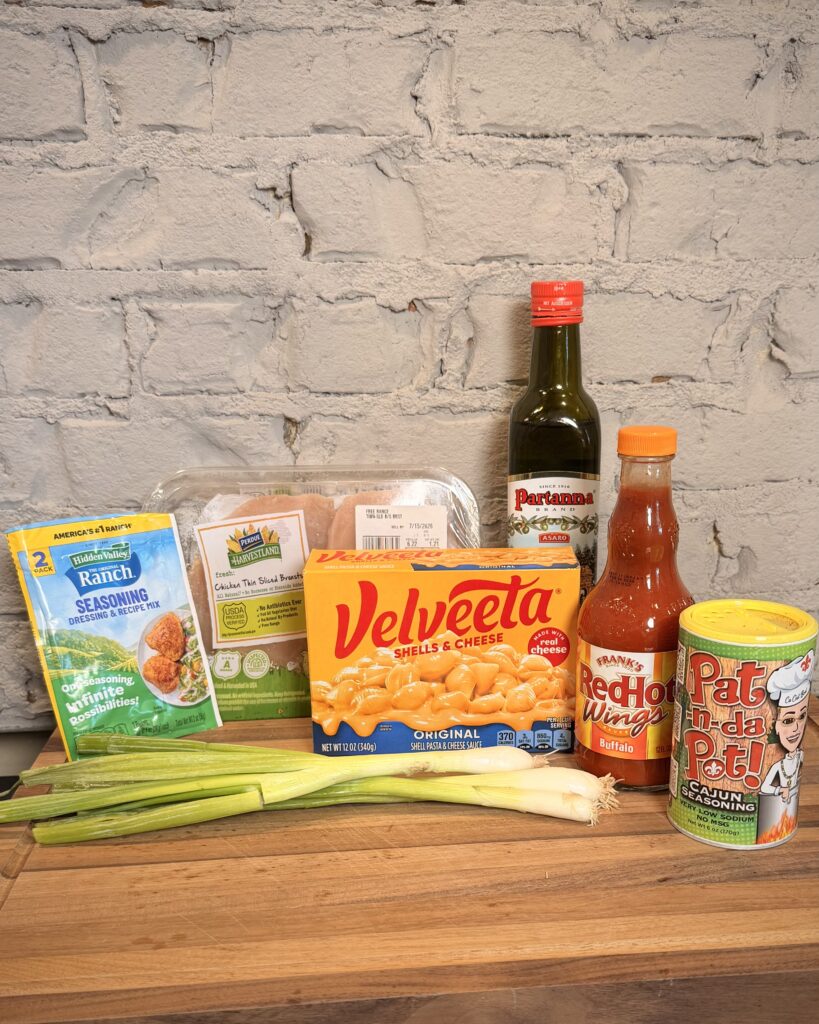 Ingredients for Buffalo Chicken Broccoli Mac N Cheese sit on a counter