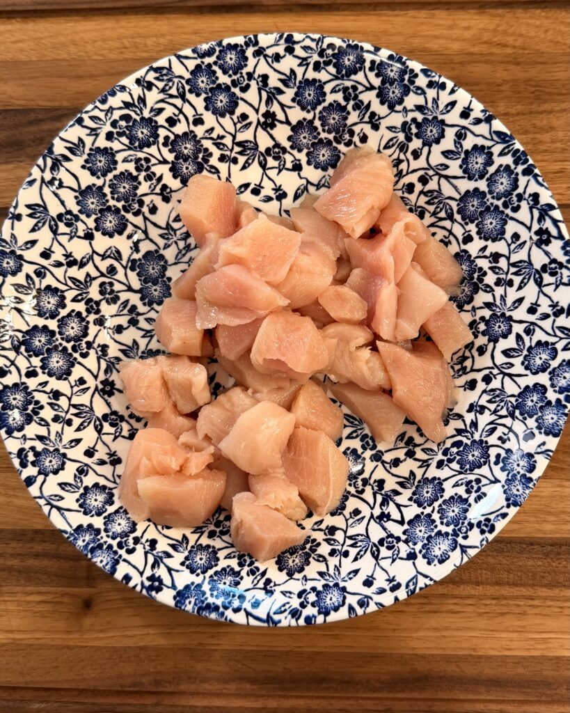 Thinly sliced chicken breast sits in a bowl before being prepared