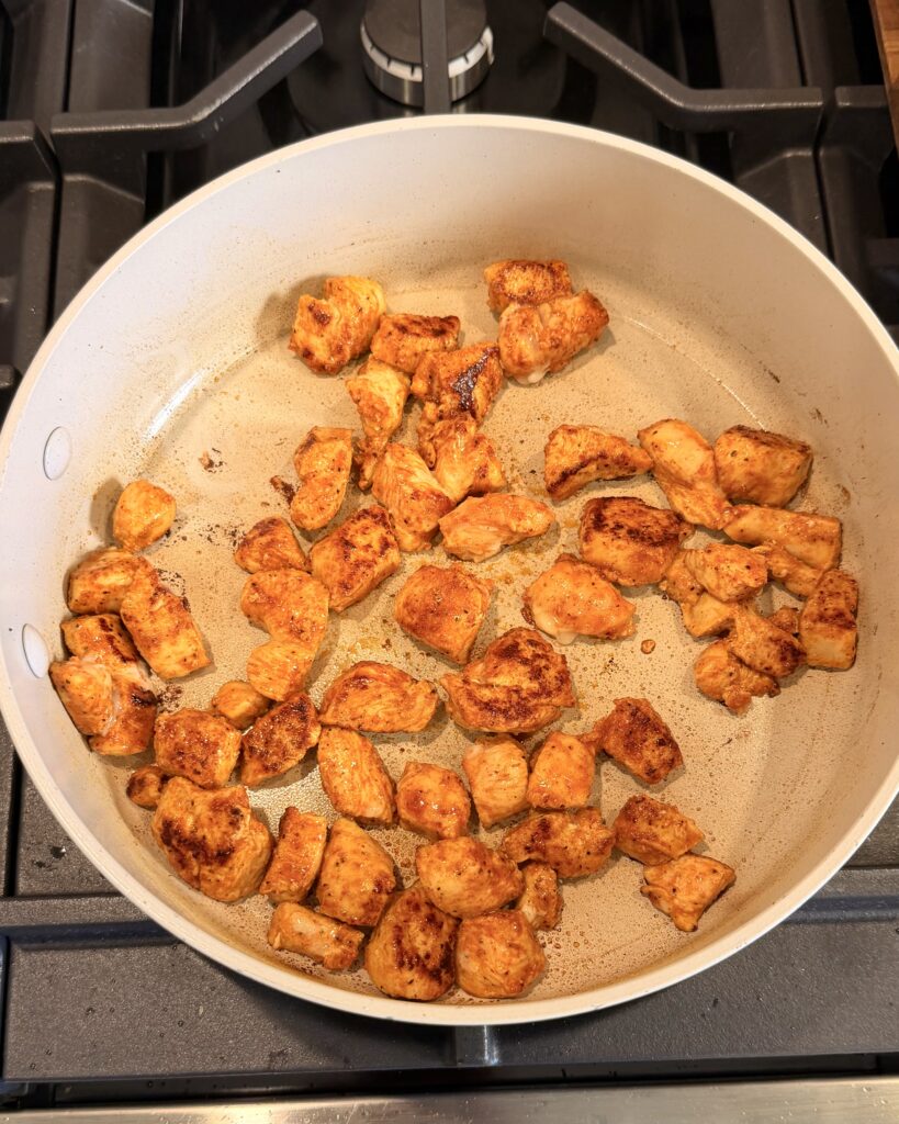 Chicken breast cooks in a large skillet after being seasoned for a dish
