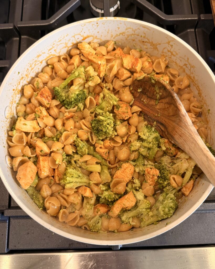 Broccoli and Velveta Mac N Cheese is added to the cooked chicken in the skillet