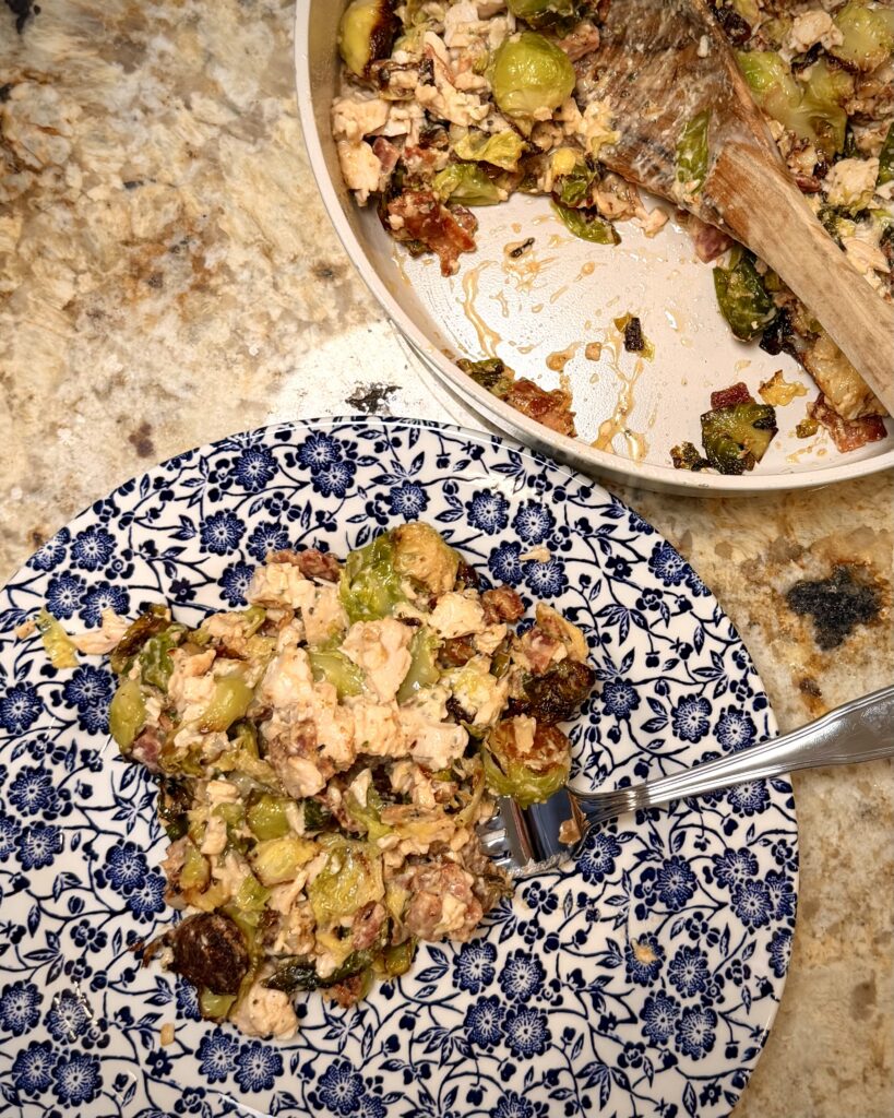 A portion of Cheesy Bacon Chicken and Brussels Sprouts cooked by Your Barefoot Neighbor Matthew Bounds on a plate next to a skillet.