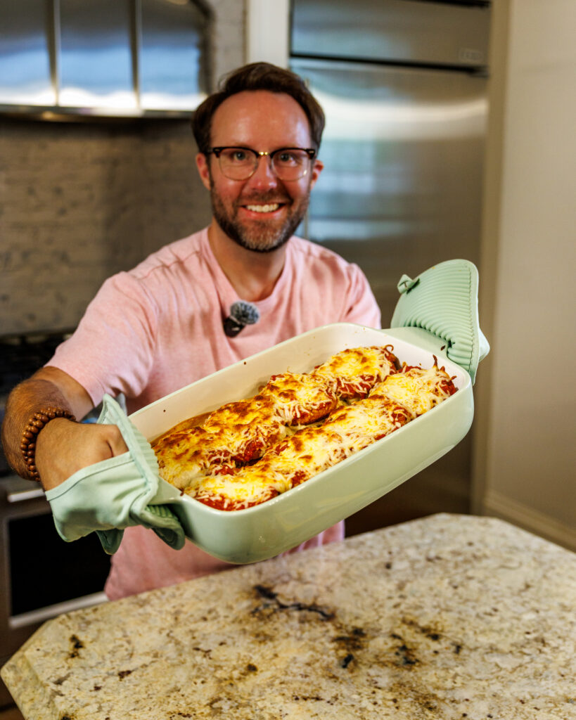 Matthew Bounds, creator of Your Barefoot Neighbor, holds a 9x13 baking dish of savory and cheesy Chicken Parm Garlic Toast