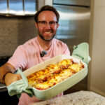 Matthew Bounds, creator of Your Barefoot Neighbor, holds a 9x13 baking dish of savory and cheesy Chicken Parm Garlic Toast