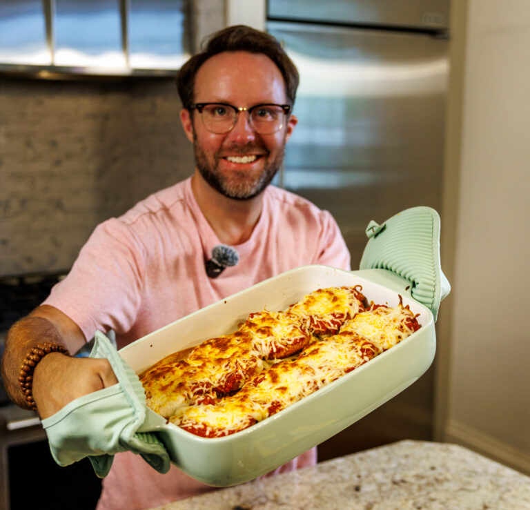 Matthew Bounds, creator of Your Barefoot Neighbor, holds a 9x13 baking dish of savory and cheesy Chicken Parm Garlic Toast