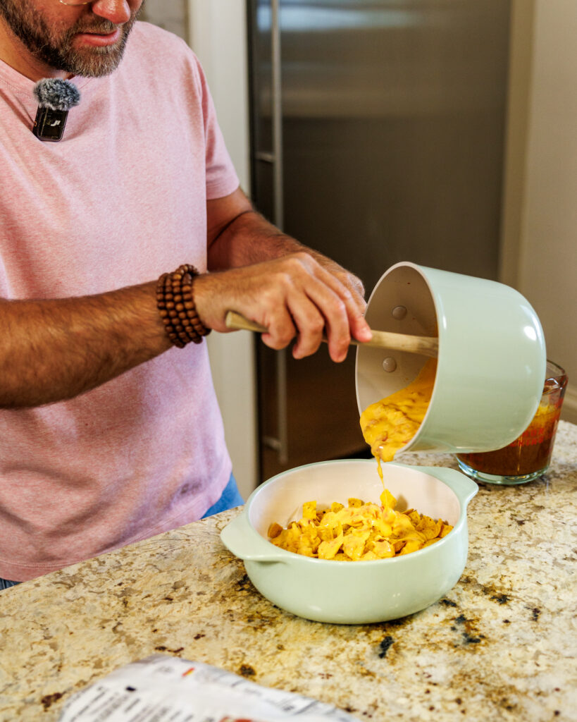 Matthew Bounds, creator of Your Barefoot Neighbor, adds cheese to a hearty bowl of Chili Frito Pie