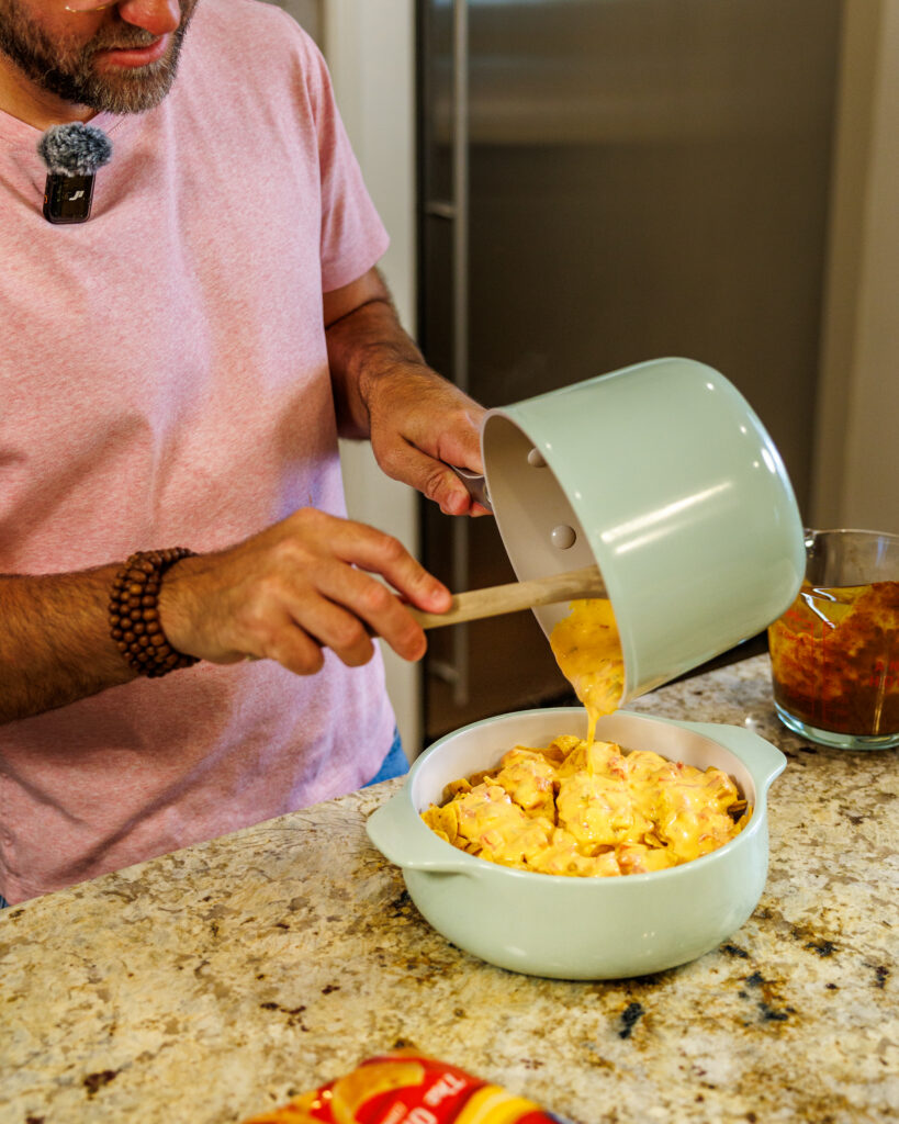 Matthew Bounds, creator of Your Barefoot Neighbor, adds cheese to a hearty bowl of Chili Frito Pie