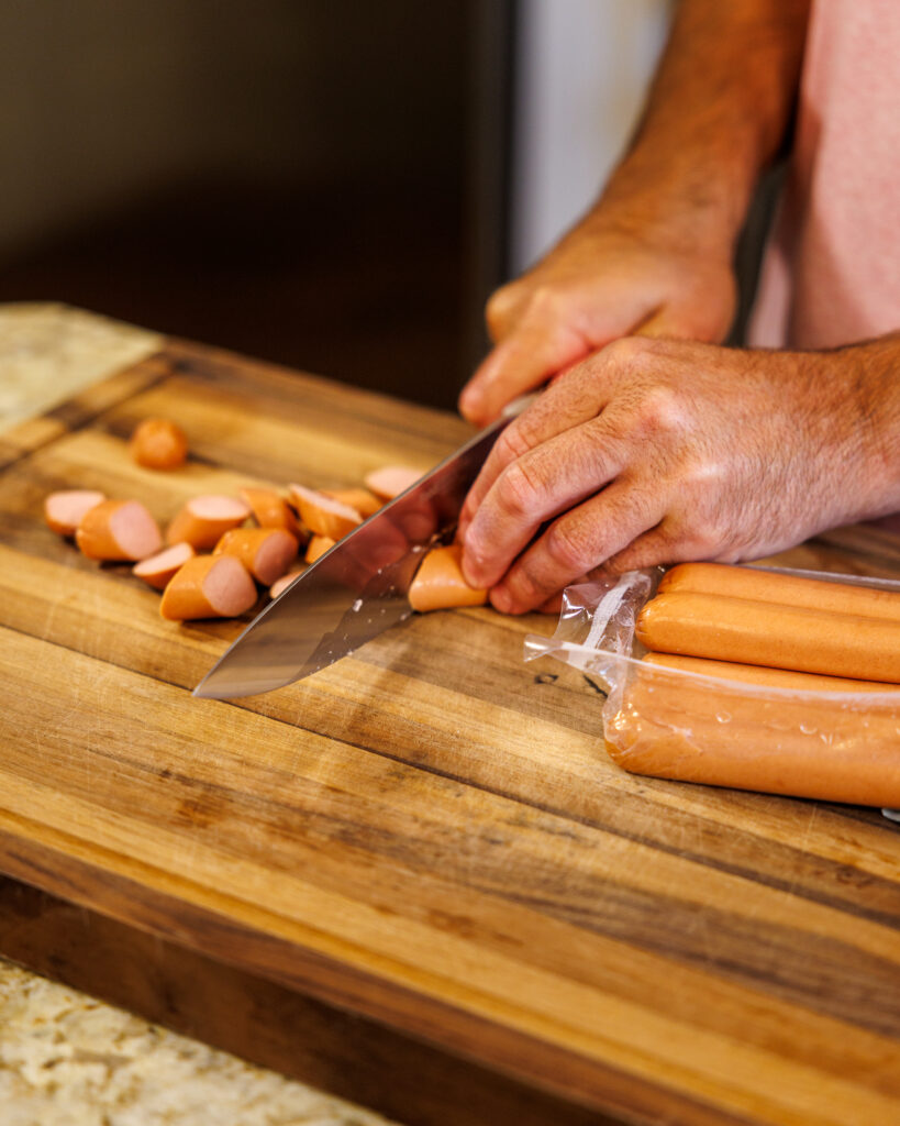 Matthew Bounds, creator of Your Barefoot Neighbor, slices hot dogs to add to his easy Corndog Casserole