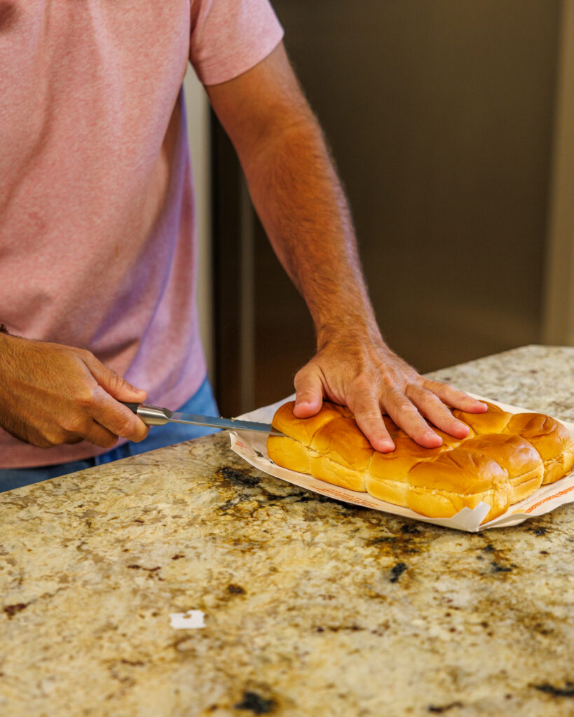 Matthew Bounds, creator of Your Barefoot Neighbor, slices the rolls for his Marry Me Chicken Sliders