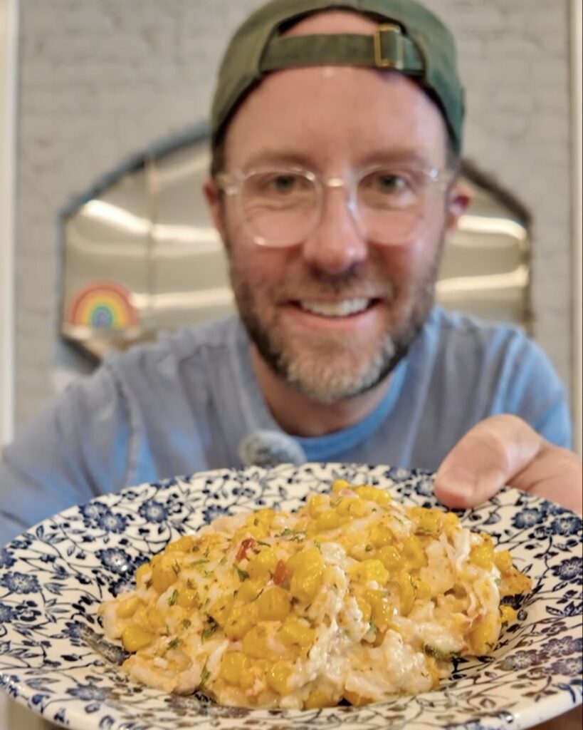 Matthew Bounds, creator of Your Barefoot Neighbor, holds a plate of Street Corn Enchilada Bake in his kitchen.