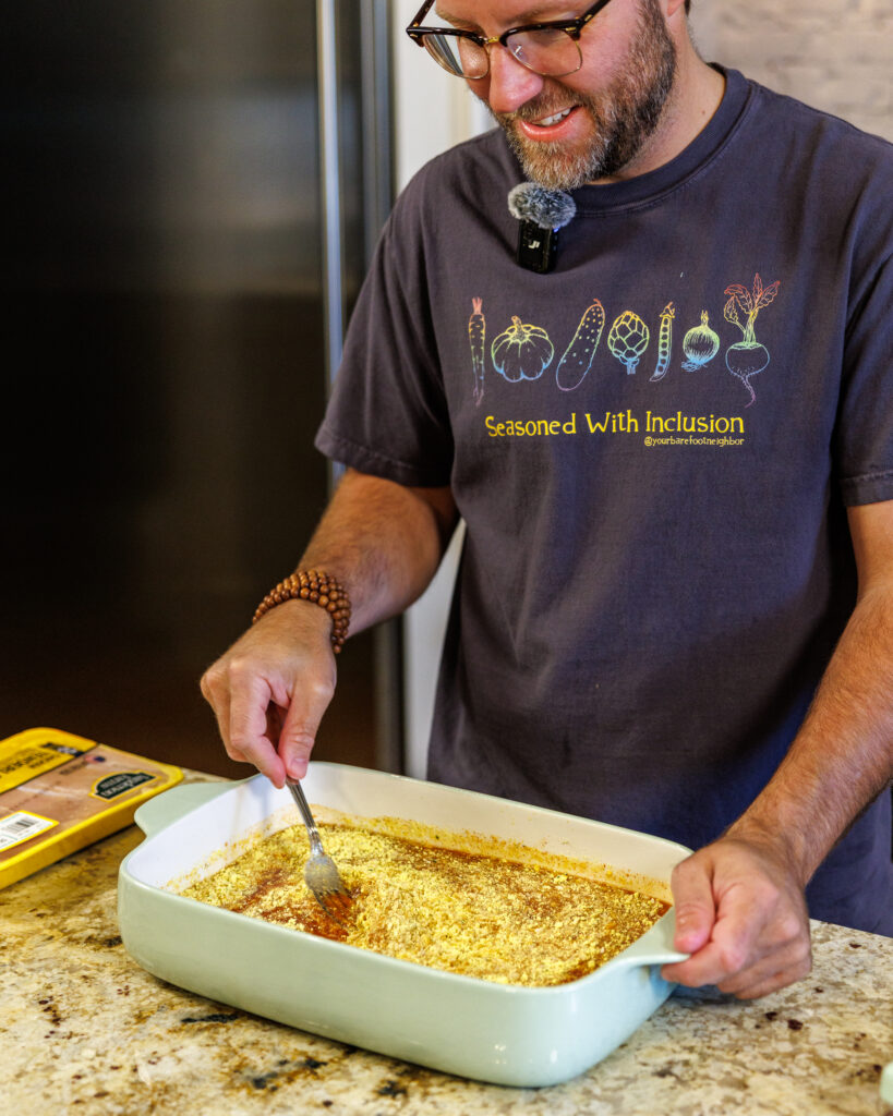 Your Barefoot Neighbor Matthew Bounds adds ingredients to his dish for his Baked Swim Queso Chicken in his kitchen