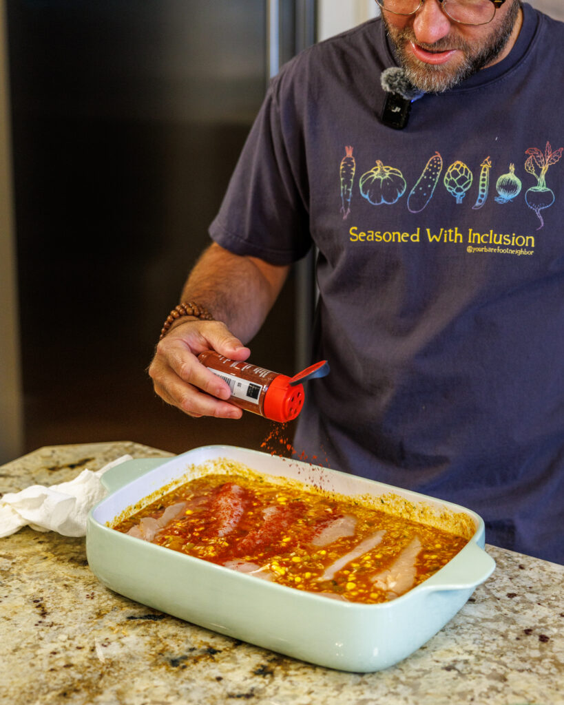 Your Barefoot Neighbor Matthew Bounds adds ingredients to his dish for his Baked Swim Queso Chicken in his kitchen