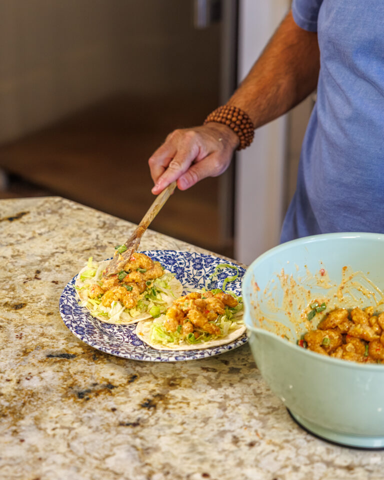 Matthew Bounds, creator of Your Barefoot Neighbor, spoons shrimp onto tortillas as part of his Bang Bang Shrimp Tacos meal