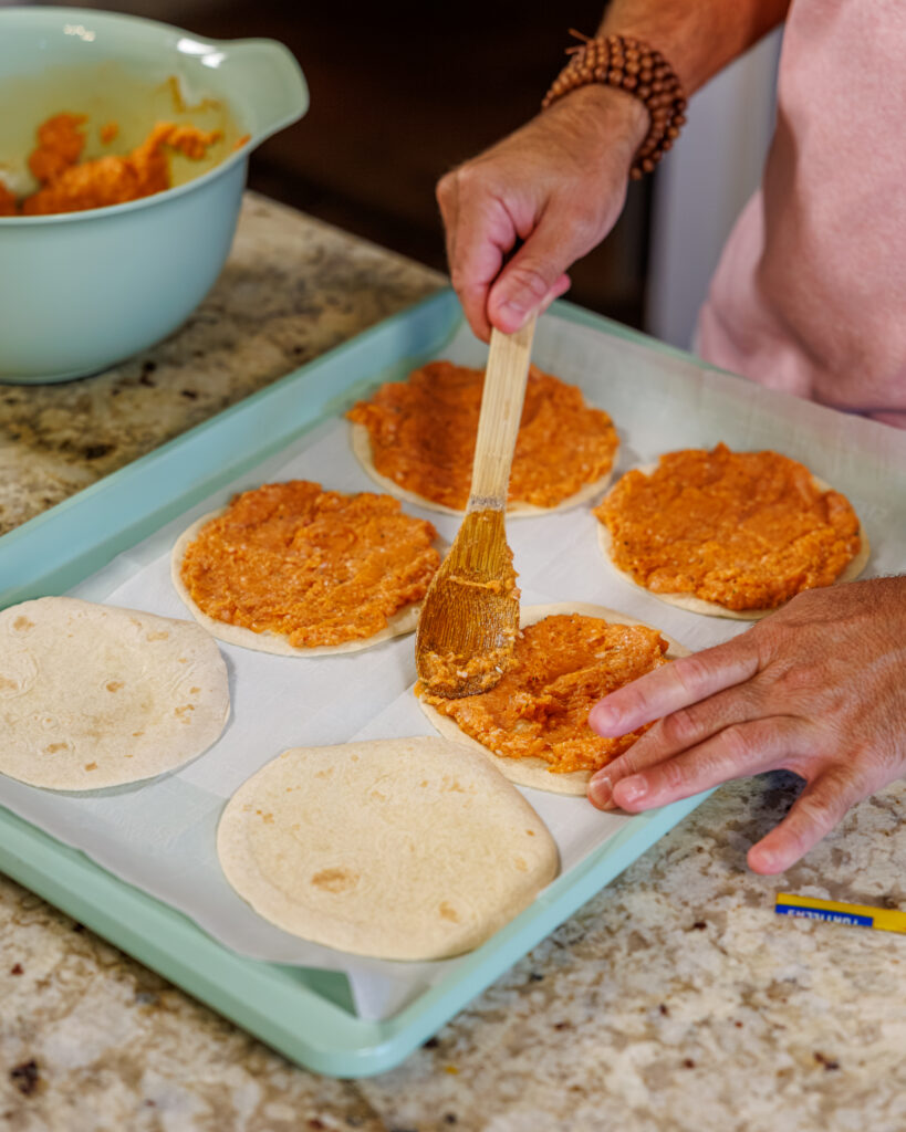Matthew Bounds, creator of Your Barefoot Neighbor, adds Buffalo sauce to a Buffalo Chicken Smash Taco