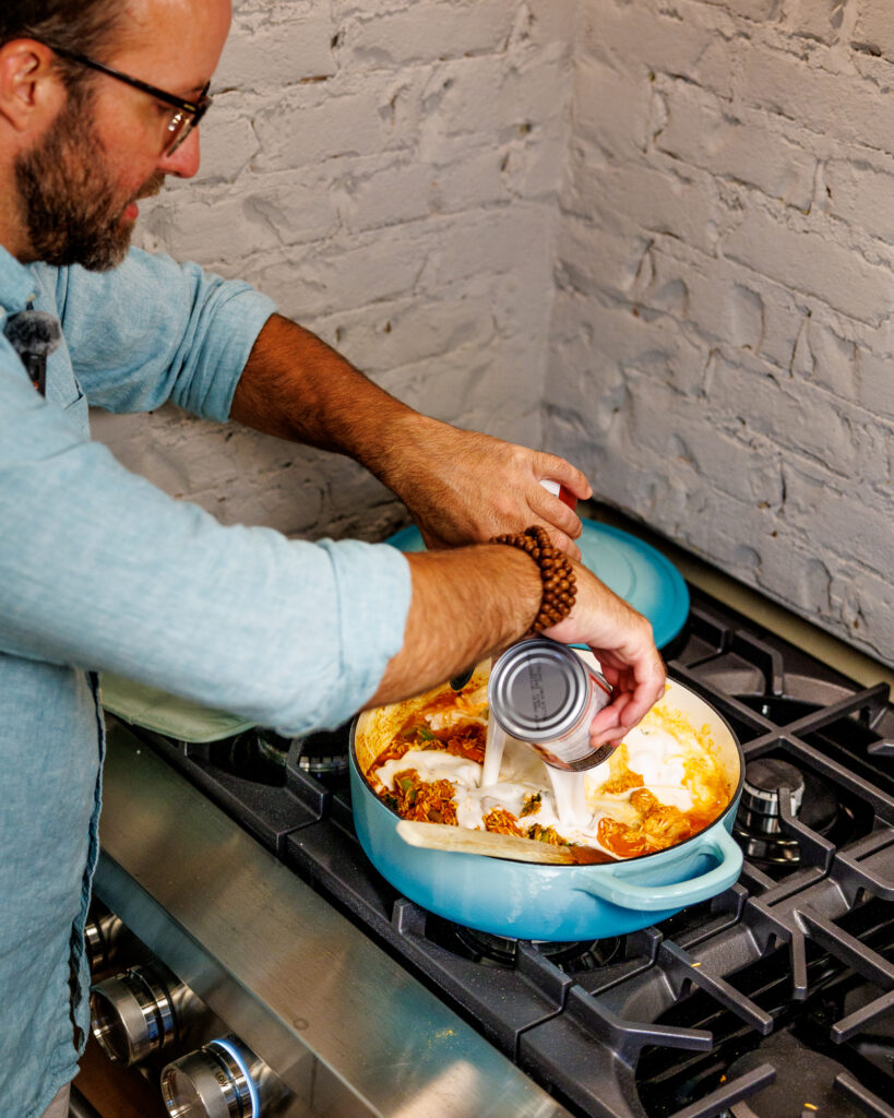 Matthew Bounds, creator of Your Barefoot Neighbor, add ingredients to his pot for Coconut Curry One Pot Chicken and Rice