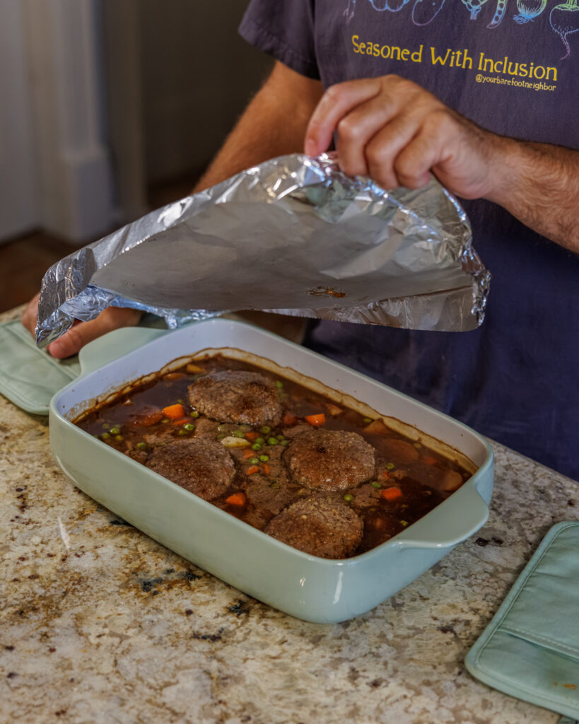 Matthew Bounds, creator of Your Barefoot Neighbor, places aluminum foil on top of a 9x13 dish for Hamburger Steaks and Gravy