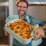Matthew Bounds, creator of Your Barefoot Neighbor, holds a 9x13 dish of Pizza Bubble Bake in his kitchen
