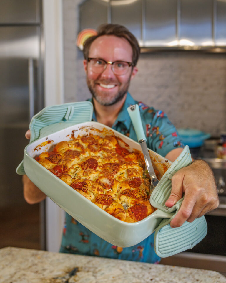 Matthew Bounds, creator of Your Barefoot Neighbor, holds a 9x13 dish of Pizza Bubble Bake in his kitchen