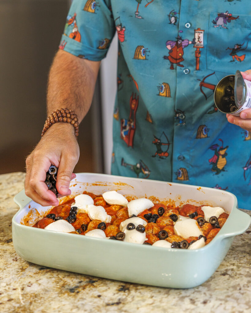 Matthew Bounds, creator of Your Barefoot Neighbor, adds olives to his Pizza Bubble Bake dish