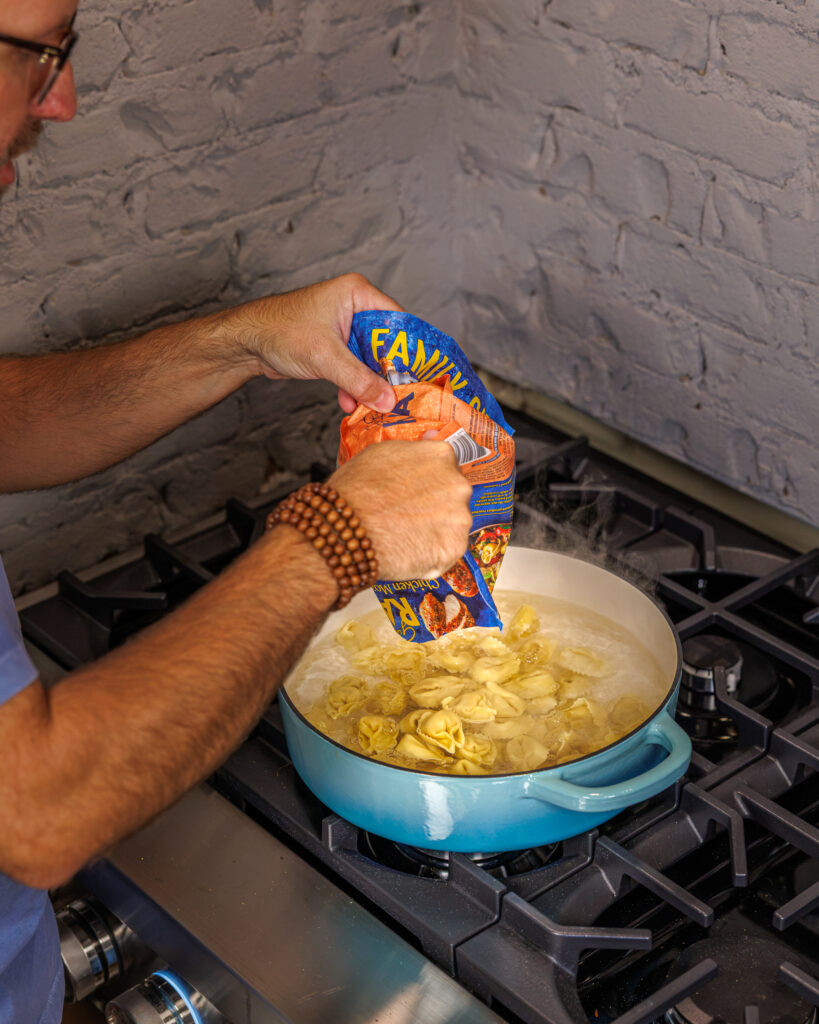 Matthew Bounds, creator of Your Barefoot Neighbor, adds ingredients to a pot for his Back to School Too Tired Tortellini