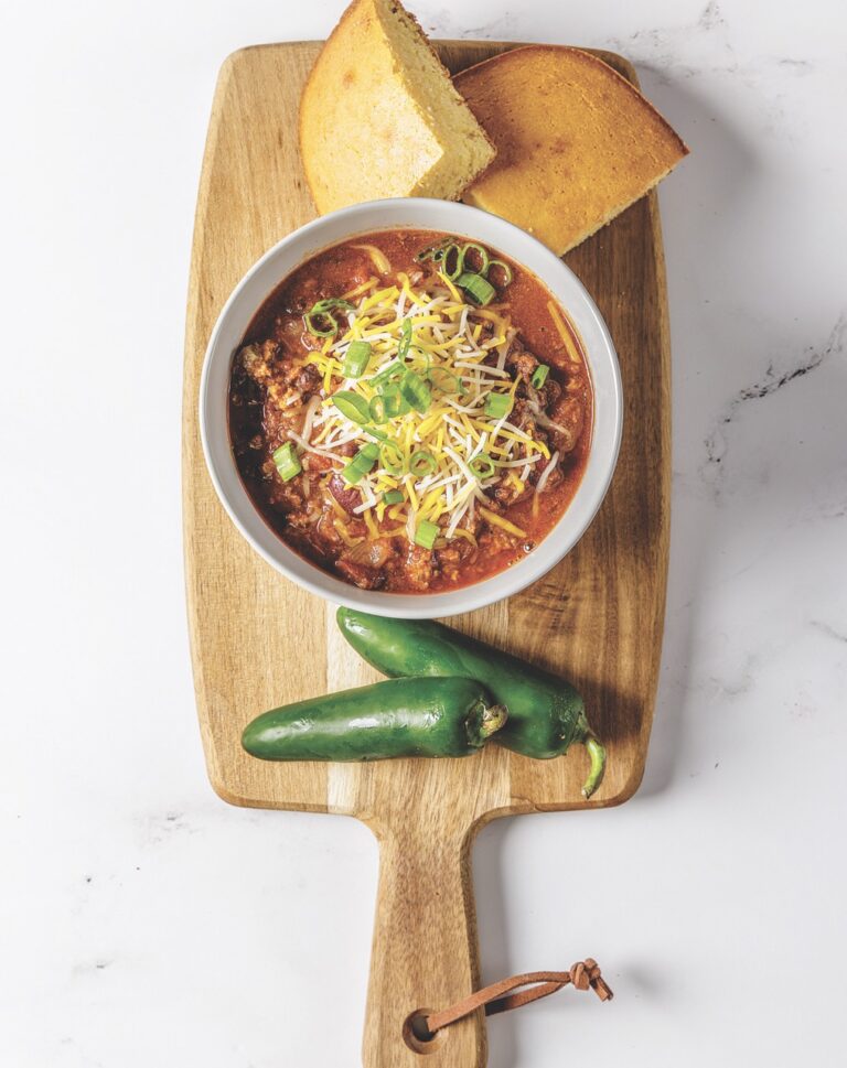 A hearty bowl of Matthew Bounds, or Your Barefoot Neighbor's, Beef Chili from Keep It Simple Y'all sits on the counter next to cornbread and fresh jalapenos.