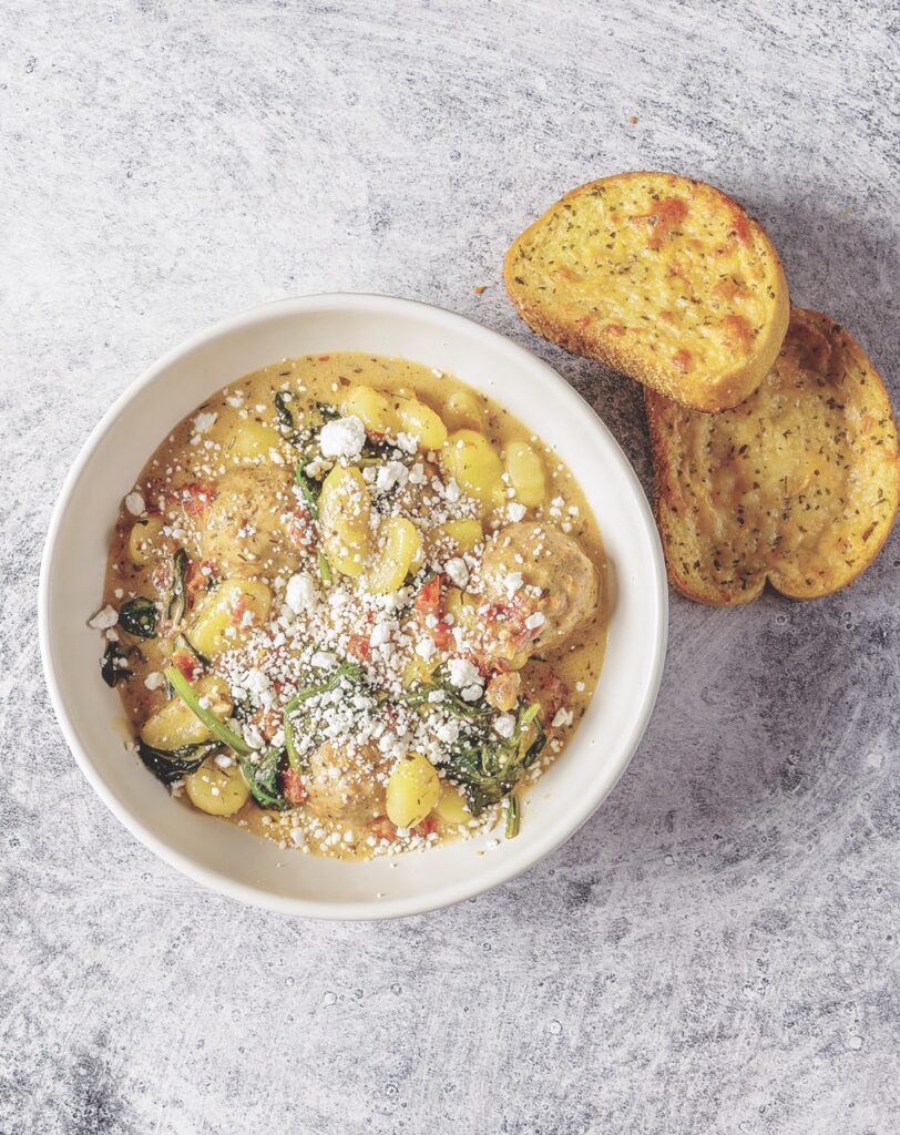 Matthew Bounds, creator of Your Barefoot Neighbor's hearty Goat Cheese Gnocchi Meatball Soup simmers in a bowl topped with cheese