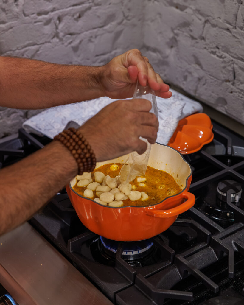 Matthew Bounds, creator of Your Barefoot Neighbor, cooks Goat Cheese Meatball Gnocchi on the stovetop in a pumpkin pot
