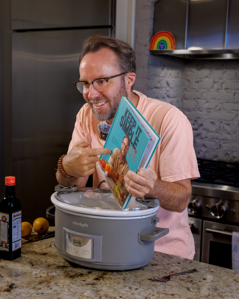 Matthew Bounds, creator of Your Barefoot Neighbor, holds a copy of his book Keep It Simple Y'all in his kitchen